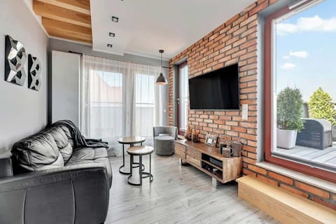 A cozy living area with modern black leather furniture, exposed brick walls, and a flat-screen TV, creating a trendy industrial vibe.