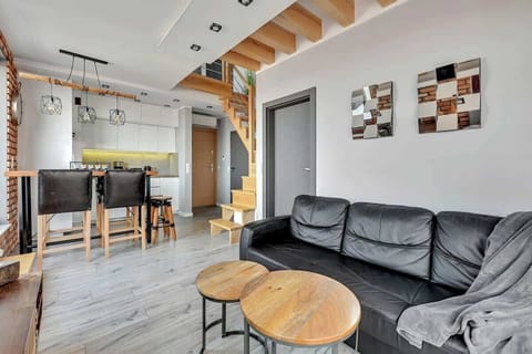 A cozy living area with modern black leather furniture, exposed brick walls, and a flat-screen TV, creating a trendy industrial vibe.