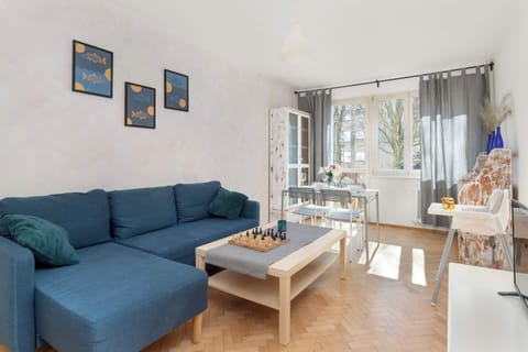 A spacious living room with a blue corner sofa, a wooden coffee table and bright walls with accents in the form of paintings on the wall.