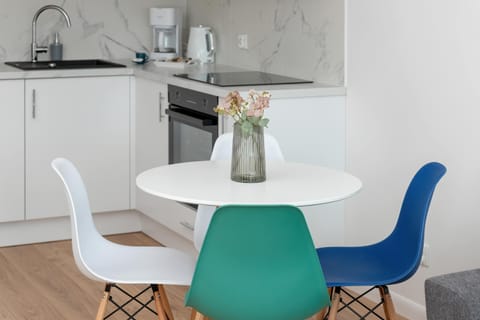 Small dining area with a round table, white chairs, and turquoise base. A charming corner for meals.

