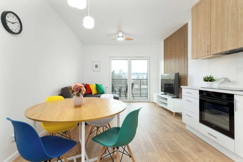 A bright open-plan living room and kitchen area with modern decor and a stylish dining set. Ideal for sharing meals or working remotely.