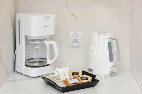 A close-up of a drip coffee maker and electric kettle on a marble counter. Everything you need for your morning brew.