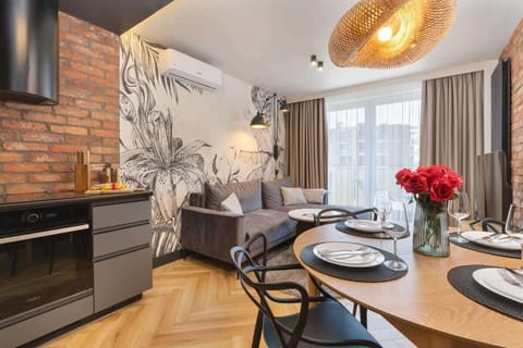 A living room with a mural wall, grey sectional sofa, and a dining area with tulips in the background.