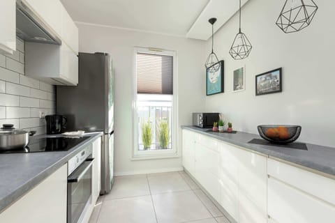 A kitchen with white cabinets, a subway tile backsplash, and large windows letting in natural light. The clean and modern aesthetic enhances the overall ambiance.