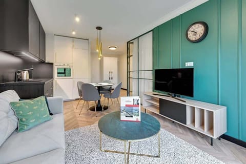Vibrant and contemporary living space features a striking blend of deep green accents, sleek black cabinetry, and modern furnishings, creating a chic and cozy atmosphere with a touch of elegance.