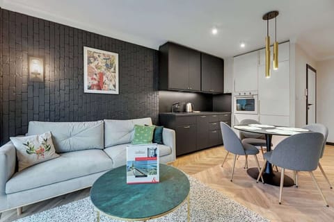 Seamlessly blends modern sophistication with artistic flair, featuring a sleek gray sofa, bold black cabinetry, and elegant gold light fixtures, all set against a textured wall that adds a unique touch to the space.