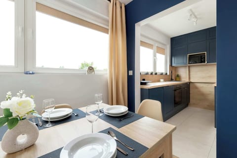 A modern dining area with a table set for four, placed near large windows allowing plenty of daylight.