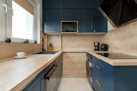 A modern kitchen with navy blue cabinets, wooden countertops, and built-in appliances.