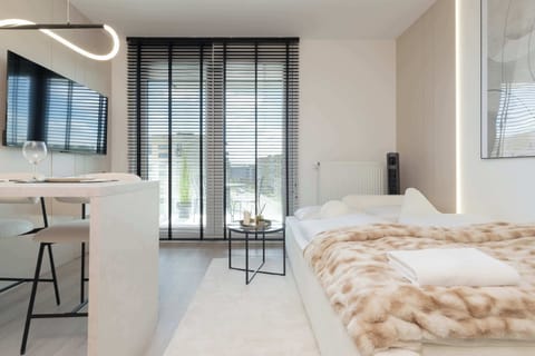 A bright studio with a round table and four chairs, set by large windows, offers a pleasant spot for shared meals.