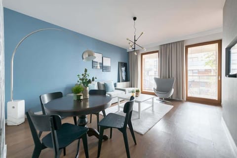 A cozy dining space featuring a wooden table and modern chairs, complemented by a soft color palette. The natural light pouring in through the large windows creates a warm and inviting atmosphere.