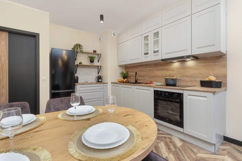 A compact, fully equipped kitchenette with white cabinets and a wooden backsplash, blending functionality with style.