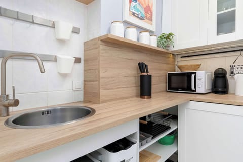 A close-up of the kitchen sink area, showing an electric kettle, a microwave, and wooden countertops.

