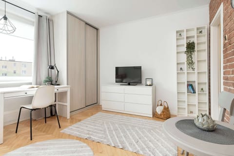 A stylishly furnished room with a bed, a small desk under the window, and minimalist decor.

