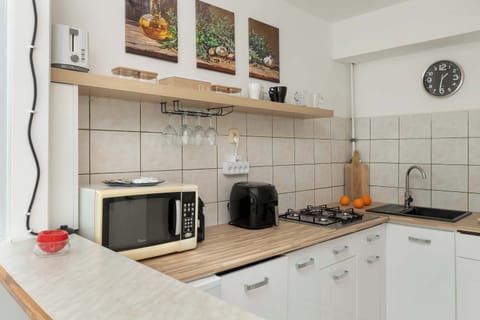 Another perspective of the kitchen highlighting the gas stove, microwave, and open shelving with cups and utensils.

