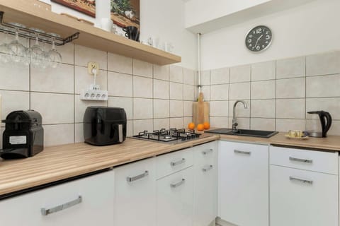 A compact yet fully equipped kitchen with white cabinets, wooden countertops, and essential appliances including a kettle and toaster.