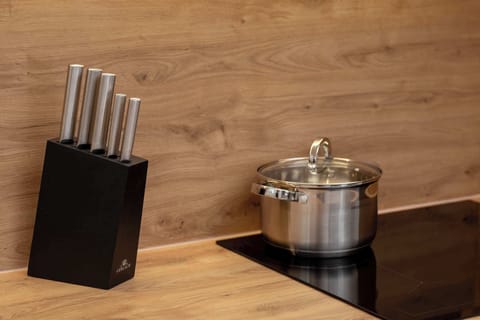 A closer look at the kitchen's wooden countertop, featuring a knife block and a pot. The backsplash and lighting enhance the warm and stylish atmosphere.