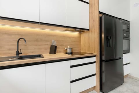 A different perspective of the kitchen, showcasing white cabinets, a black refrigerator, and a sleek, modern design. The kitchen is well-lit and spacious.