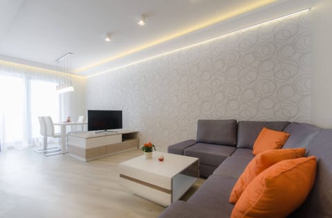 A bright and modern living area with a comfortable sofa, TV, and soft lighting.
