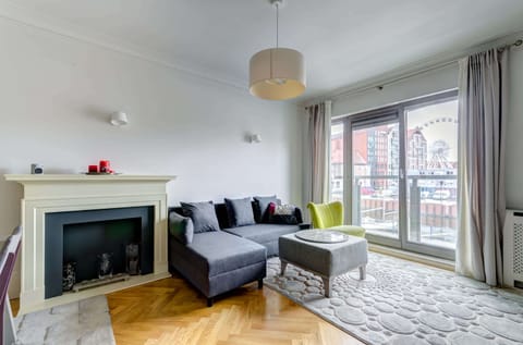 A stylish and cozy living area featuring a large window, sofa, and a decorative fireplace.