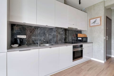 A white minimalist kitchen with a grey countertop and built-in appliances.