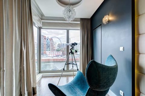 Stylish reading nook with a turquoise accent chair and city views.