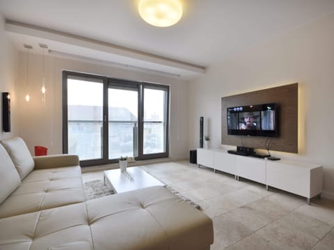 The spacious living room is designed as a space for relaxation and spending quality time together. A large corner sofa ensures comfort, whether you're reading a book or enjoying your favorite movies on a modern flat-screen TV.