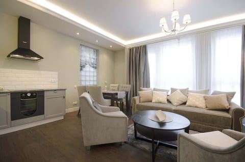 The living room is decorated in an elegant and classic style, which impresses with a harmony of light, muted colors and tasteful accessories. In the center of the room is a large, soft sofa in a subtle shade of beige, decorated with numerous pillows