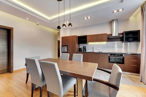 A spacious dining setup with a wooden table and upholstered chairs, surrounded by natural light from large windows.