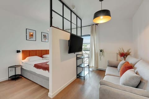 A modern interior in light colors with loft accents, combining functionality with a cozy atmosphere thanks to warm orange accessories.
