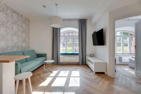 Modern, minimalist style, with a soft green velvet sofa, sleek chrome tables, and large windows allowing abundant natural light, creating a fresh, inviting, and airy atmosphere.