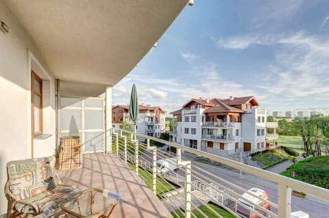 A balcony view showing the surrounding residential area with green trees and modern buildings.