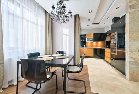 A sophisticated dining area highlighted by a glass table, elegant chairs, and a crystal chandelier.
