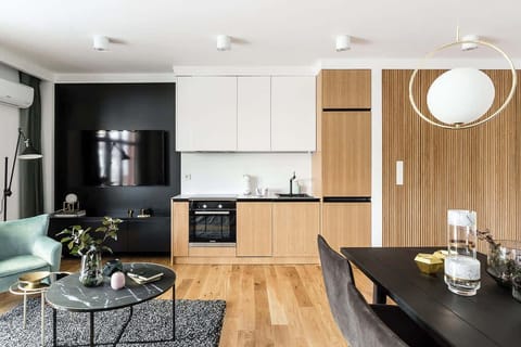 Kitchenette with a black countertop, open to the living room. The space is stylishly designed with wooden accents and sleek black finishes.