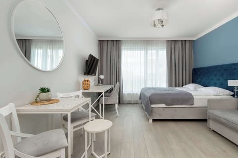 Bright space featuring a round mirror, white table, and a soft grey sofa.