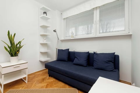 A small bedroom with a blue sofa, white shelves, and a minimalist design.