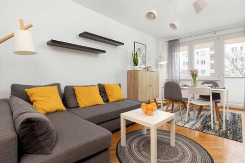 A modern living room with a gray sofa, yellow accent pillows, a coffee table, and a stylish rug. The room has a cozy, contemporary feel.
