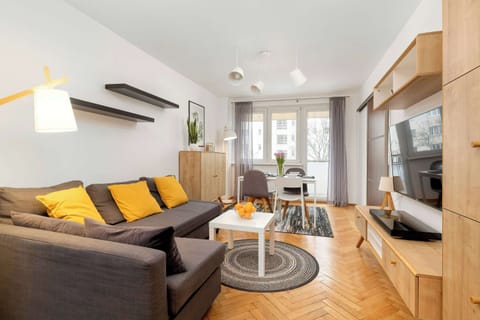 A modern living room with a gray sofa, yellow accent pillows, a coffee table, and a stylish rug. The room has a cozy, contemporary feel.