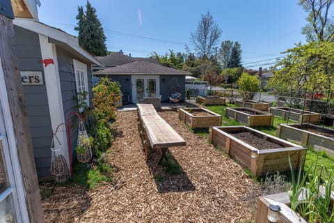 Outdoor long table dining amongst the vegetable garden beds.