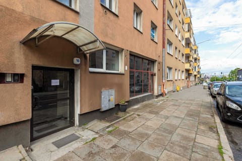A well-maintained, multi-story townhouse with a brown facade and a glass-paneled entrance marked with the number “10”, surrounded by a paved sidewalk, presents an elegant and sturdy appearance in a calm urban setting.