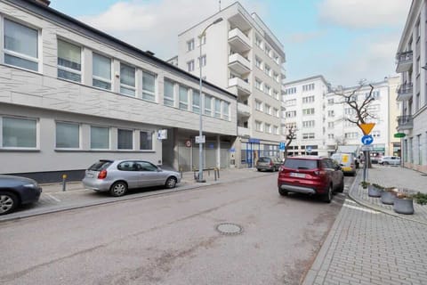 An exterior view of the building located in a quiet urban area with street parking.