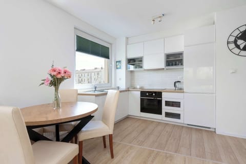 Dining area and kitchenette equipped with white cabinets and sleek appliances.