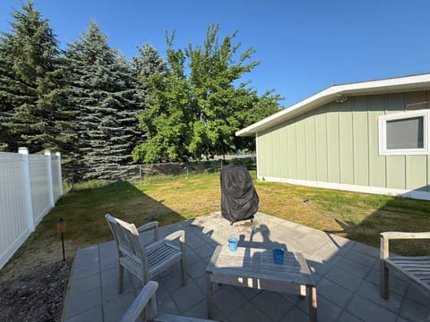 Newly fenced backyard with raised patio with teak furniture and new grill.