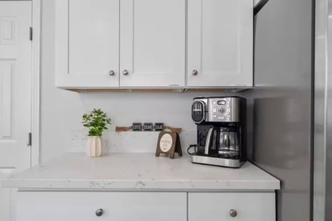 Inviting coffee bar with white cabinets, wood shelf, and cheerful morning setup.