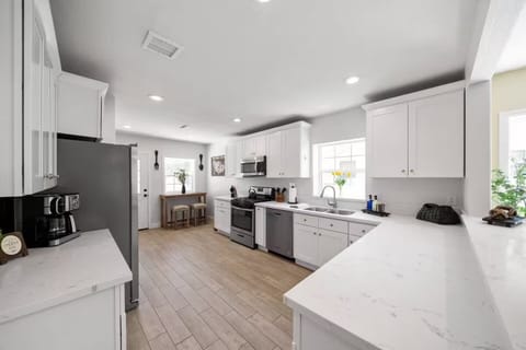 Bright kitchen with white cabinets, sleek appliances, and warm wood flooring