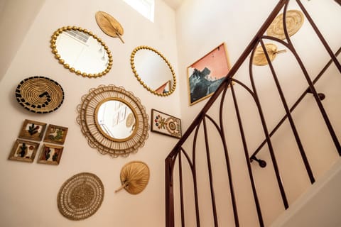 This two-story home features a beautifully designed staircase at its center, adorned with a stylish gallery wall of woven textures, mirrors, and artwork. A unique and inviting touch that adds warmth and character to the space.