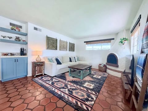 This Southwestern-style living room features handcrafted Saltillo tile, a cozy beehive fireplace, and a plush pullout queen sized sofa. Rustic wood accents, a bold area rug, and a smart TV blend comfort and charm with desert-inspired design.