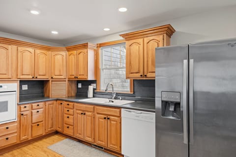 Modern kitchen with a refrigerator, dishwasher, and a sink by the window, perfect for cooking and enjoying natural light.