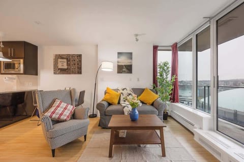 Expansive living room with abundant natural light and stunning water views. Comfortable sofa and stylish armchair create a cozy atmosphere. Open to the kitchen, making it ideal for socializing. Access to balcony for fresh air.