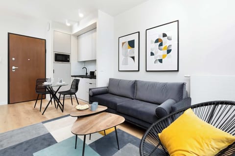 A view of the studio entrance with an elegant coffee table and a sofa decorated with stylish cushions.