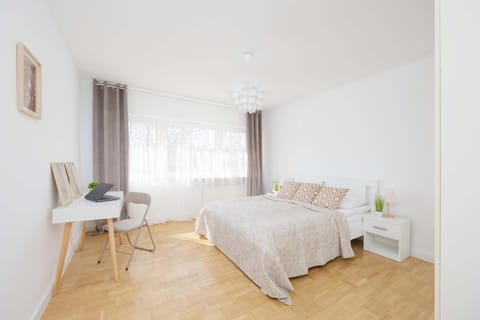A comfortable bedroom with a desk and large window supports both rest and remote work.
